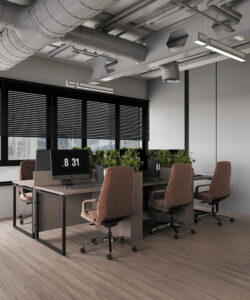 Dubai office interior featuring four brown swivel chairs, white workstations with black monitors, green plant dividers, and natural light—designed by House of Kalaa.
