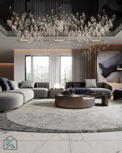 Dubai living room featuring a large gray sectional sofa, round coffee table, crystal chandelier, abstract artwork, and marble flooring—designed by House of Kalaa.