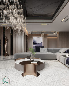 Dubai living room featuring a large gray sectional sofa, crystal chandelier, round coffee table, contemporary artwork, and wood-paneled walls—designed by House of Kalaa.