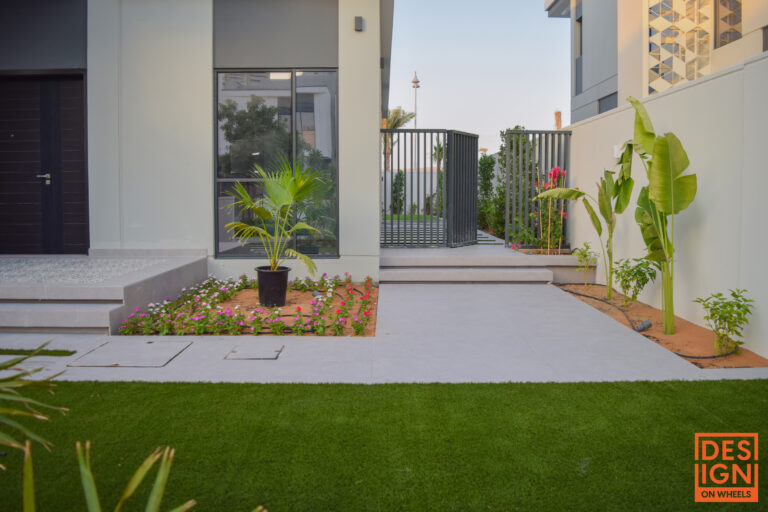 Modern Dubai garden design with tropical landscaping and lush plants beside a luxury villa entrance.
