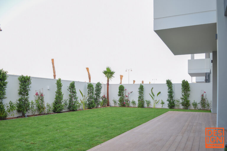Luxurious modern backyard in Dubai with green lawn, tropical plants, and wooden deck for outdoor living.