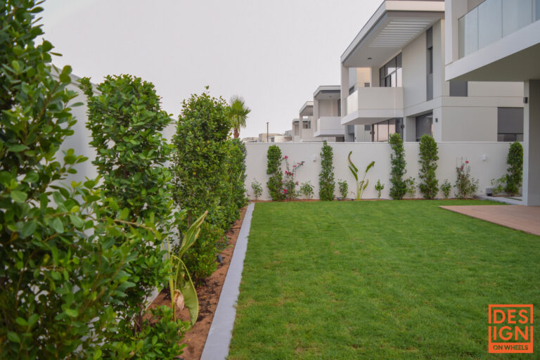Villa back garden with natural green grass and neatly arranged low-level plants for a clean and open landscape look.