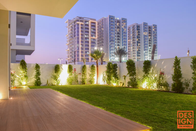 Villa backyard in Dubai with natural green grass, soft night lighting, and elegant modern landscape design.