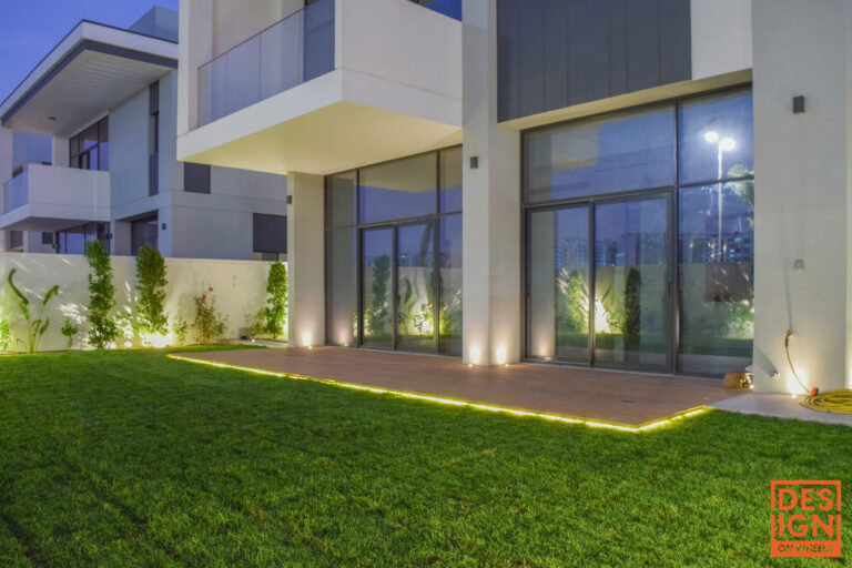 Modern villa garden lighting design in Dubai with manicured lawn, ambient wall lights, and minimalist architecture at night.