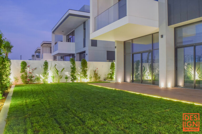 Contemporary backyard design with green lawn, garden lighting, and modern architecture by Design on Wheels.